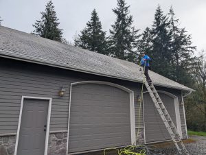 Soft washing one of the common types of roofs in Vancouver WA to remove moss and buildup