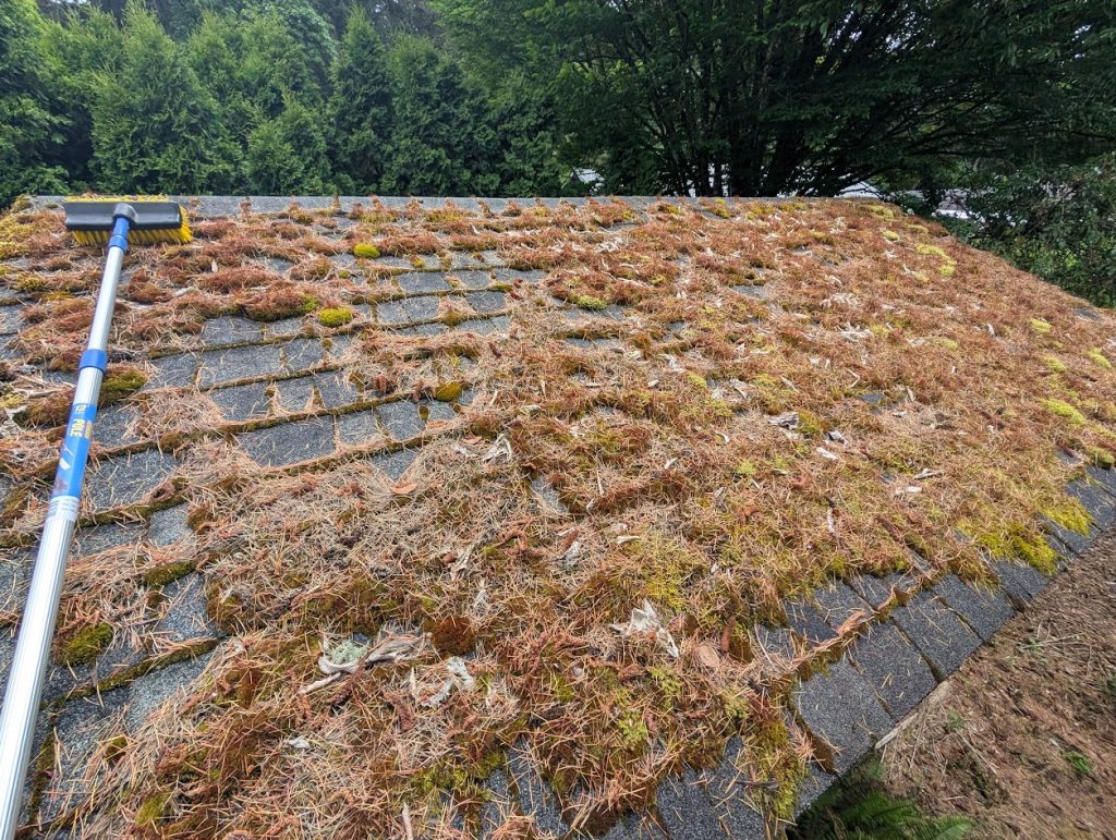 roof with leaves and debris being cleaned with a broom